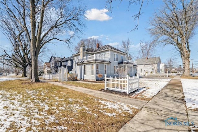 exterior space with a fenced front yard, a chimney, a residential view, and a balcony