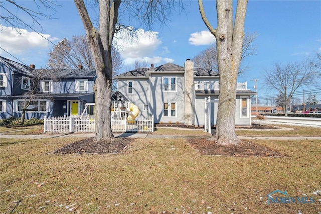 view of front of house with covered porch, a front lawn, a chimney, and fence