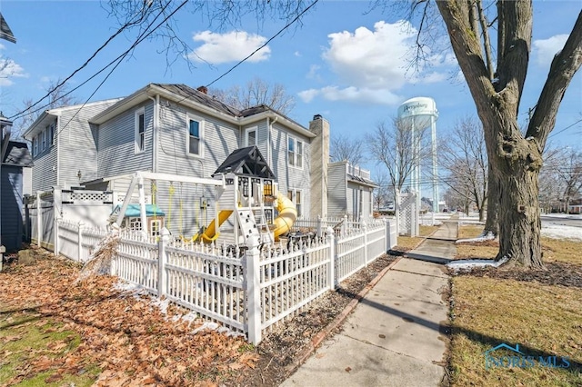 view of property exterior with a chimney, fence, and playground community