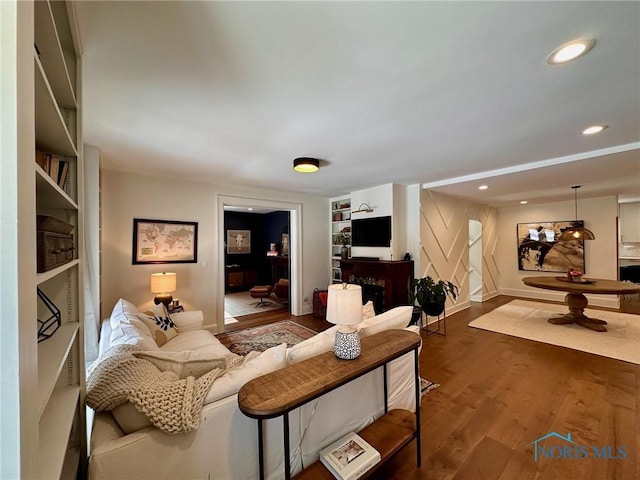 living area with baseboards, wood finished floors, and recessed lighting