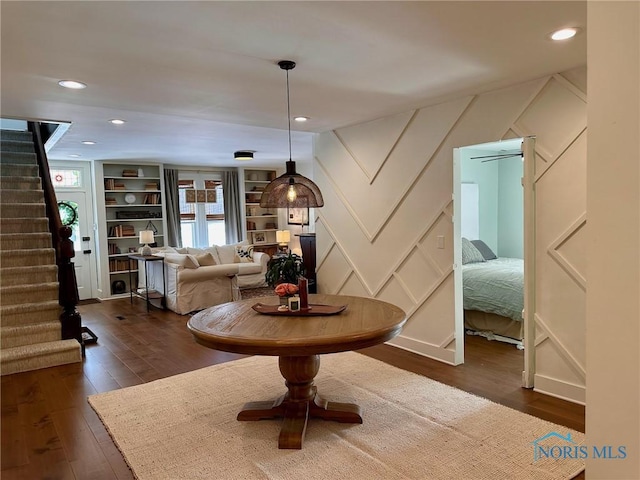 interior space with stairway, dark wood-type flooring, built in shelves, a decorative wall, and recessed lighting