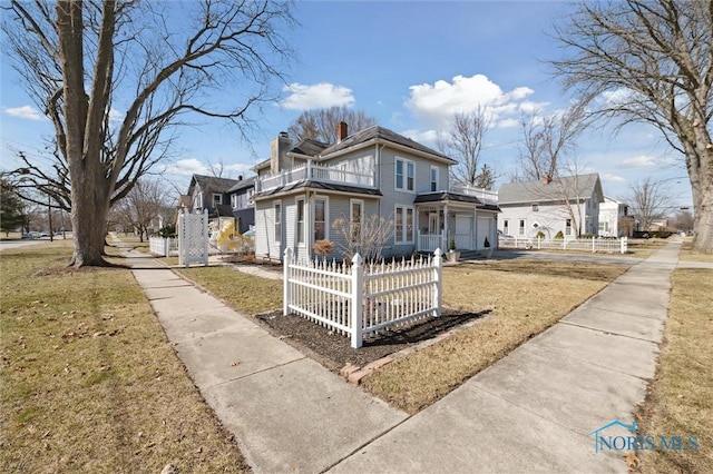 view of front of property featuring a fenced front yard, a front yard, a garage, a balcony, and a chimney