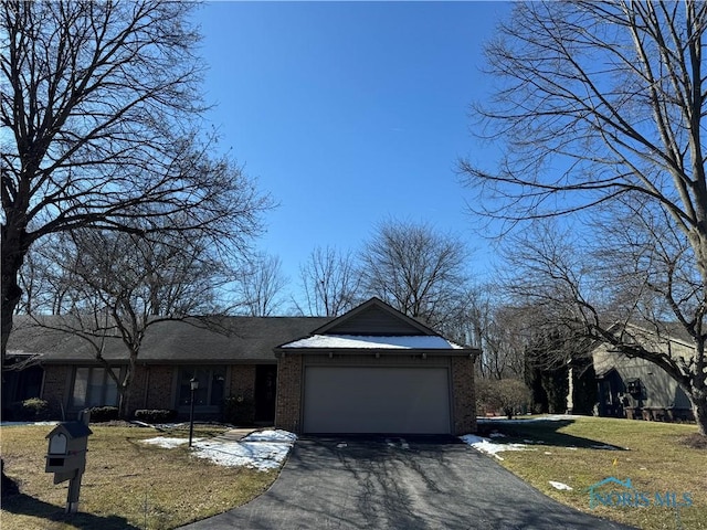 view of front of house featuring driveway, an attached garage, a front yard, and brick siding