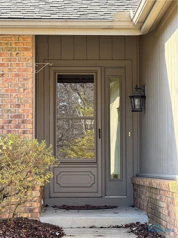 entrance to property with brick siding and roof with shingles