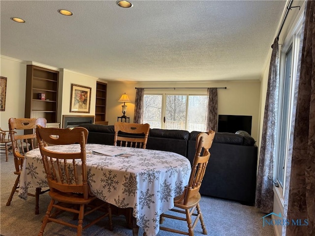 dining space featuring carpet, a fireplace, recessed lighting, ornamental molding, and a textured ceiling