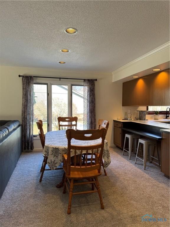 dining room featuring ornamental molding, a textured ceiling, and light colored carpet