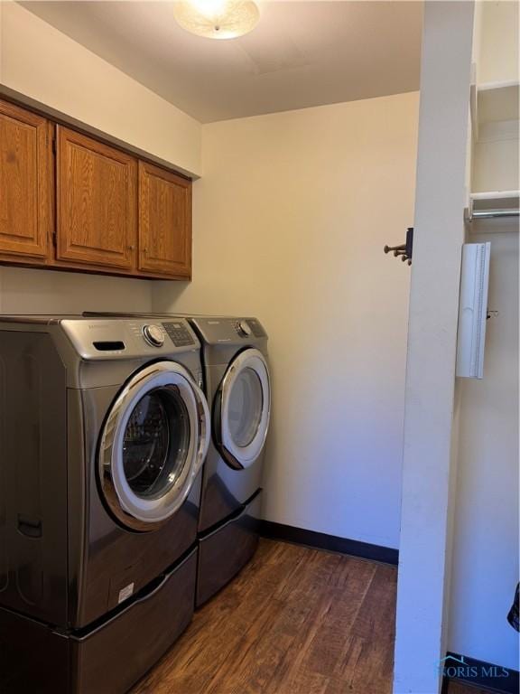 laundry area with dark wood-style flooring, cabinet space, washer and clothes dryer, and baseboards