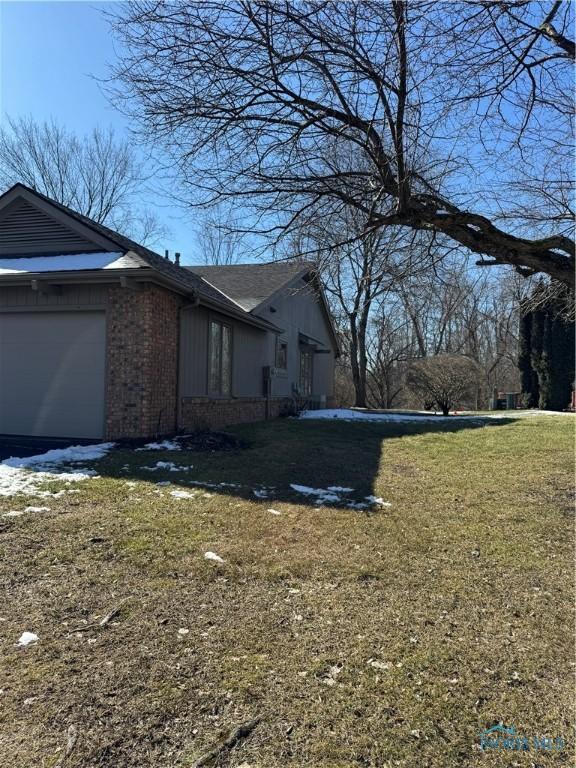 view of home's exterior with a garage, brick siding, and a lawn