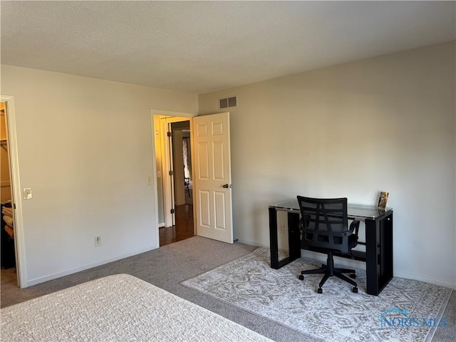 office space with a textured ceiling, carpet flooring, visible vents, and baseboards