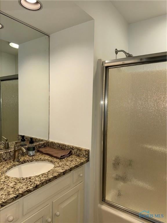 bathroom featuring bath / shower combo with glass door and vanity