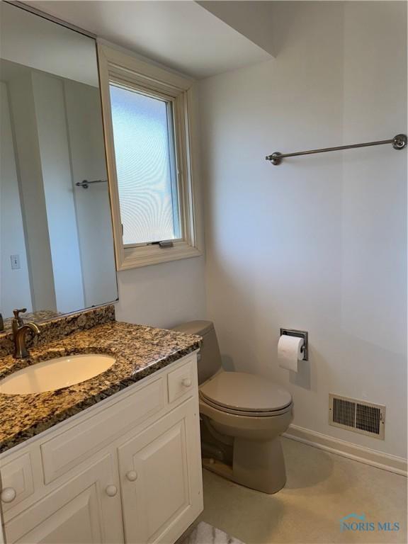 bathroom with toilet, vanity, visible vents, and baseboards