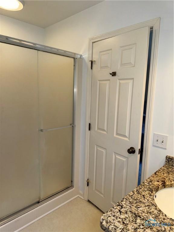 full bathroom featuring a shower with shower door and a sink