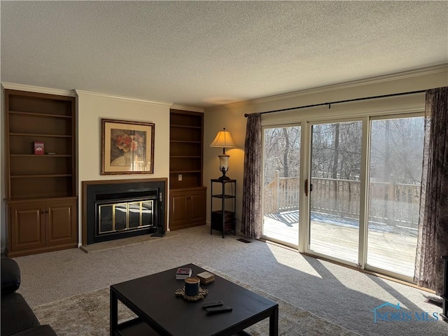 living area with carpet floors, a glass covered fireplace, and crown molding