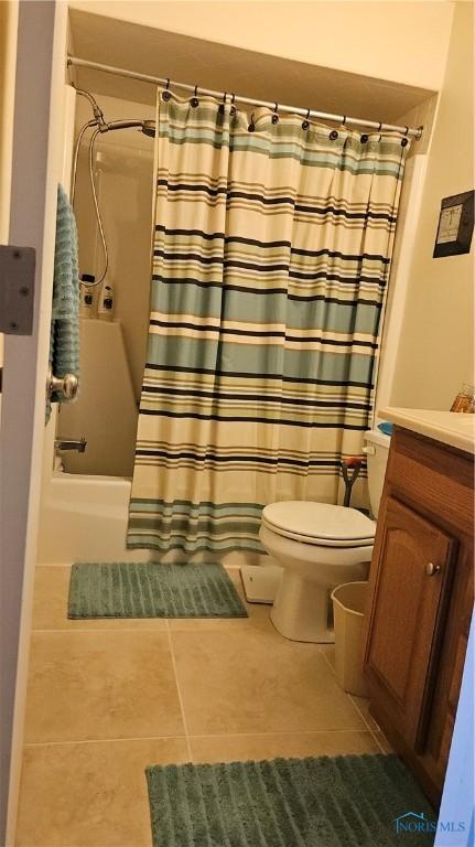 bathroom with toilet, shower / bathtub combination with curtain, vanity, and tile patterned floors