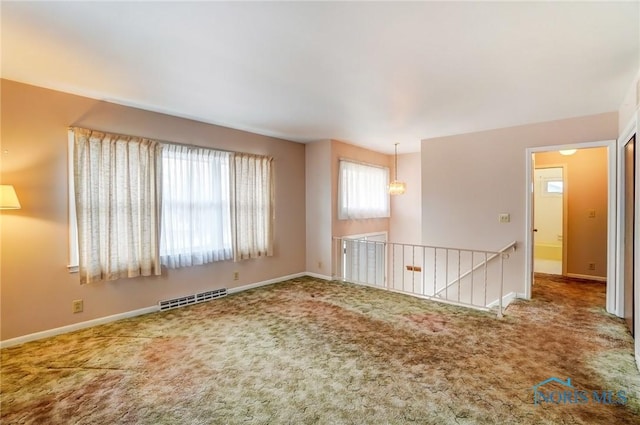 carpeted spare room featuring visible vents and baseboards