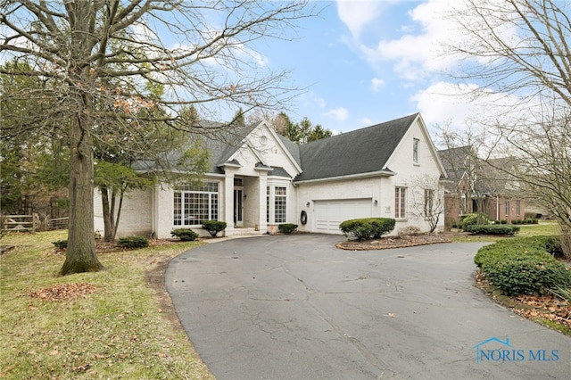 view of front of house featuring driveway, an attached garage, roof with shingles, and stucco siding