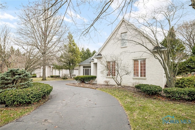 view of front of home featuring brick siding and aphalt driveway