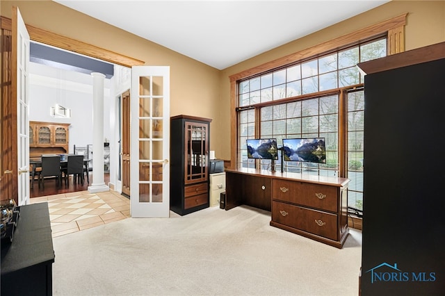 office space featuring light carpet, decorative columns, lofted ceiling, and a healthy amount of sunlight