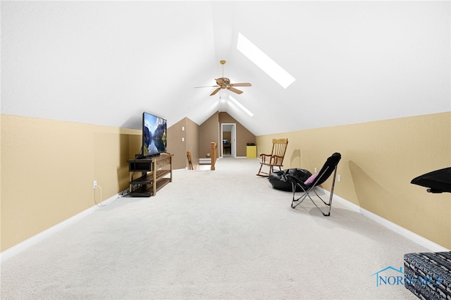 sitting room with baseboards, lofted ceiling with skylight, carpet flooring, and a ceiling fan