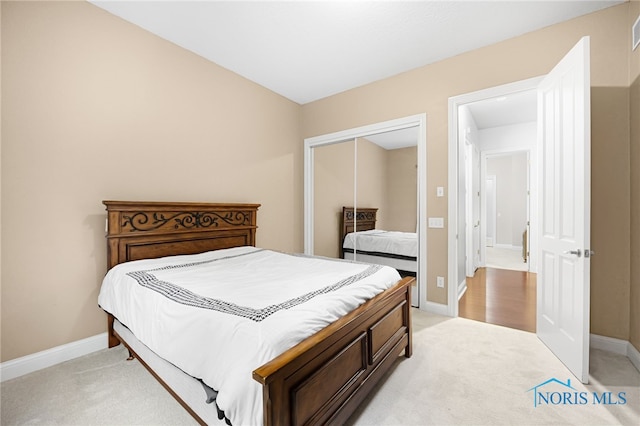 bedroom featuring a closet, baseboards, light colored carpet, and visible vents