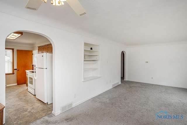 unfurnished room featuring visible vents, arched walkways, and built in shelves