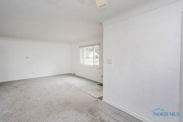 spare room featuring carpet and baseboards