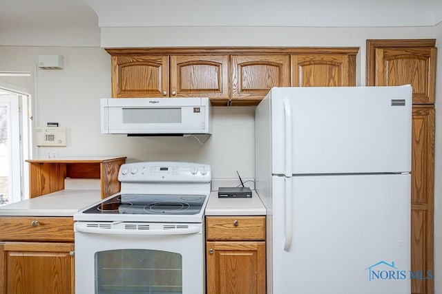 kitchen featuring brown cabinets, white appliances, and light countertops