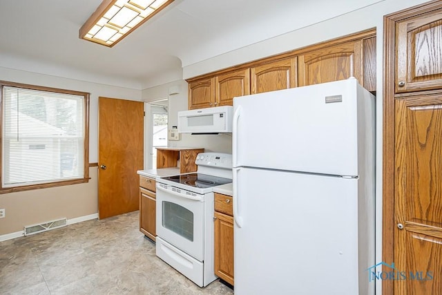 kitchen featuring white appliances, brown cabinetry, visible vents, baseboards, and light countertops