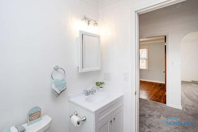 bathroom with toilet, vanity, and baseboards