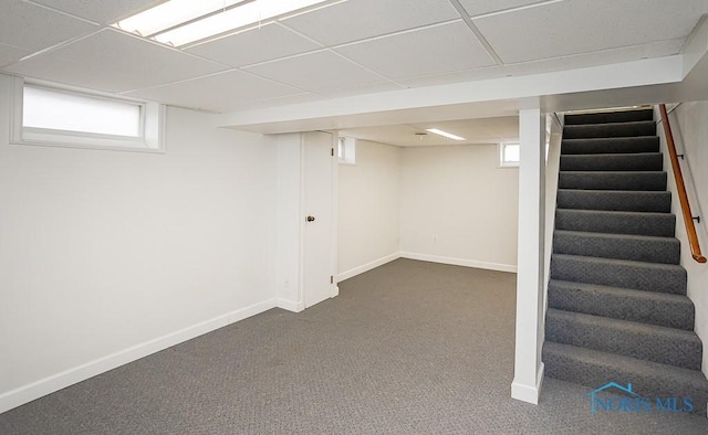 basement with dark colored carpet, stairway, baseboards, and a paneled ceiling