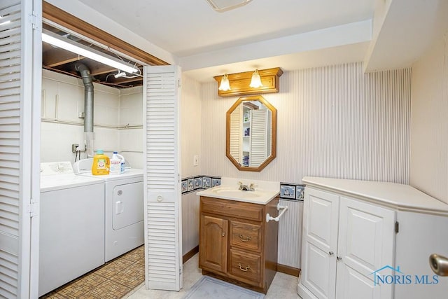 washroom with laundry area, washing machine and dryer, and a sink