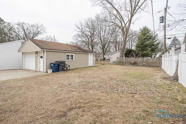 view of yard featuring an outbuilding, a garage, and fence