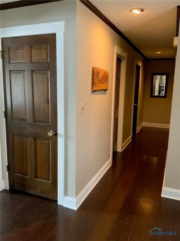 hall featuring baseboards, dark wood-style flooring, and crown molding