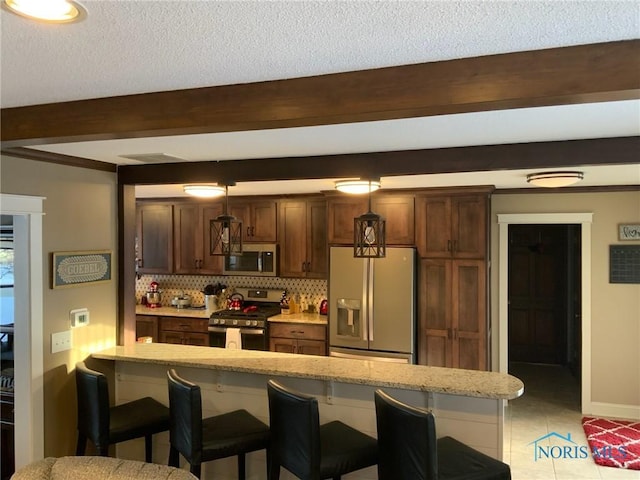 kitchen with beamed ceiling, backsplash, appliances with stainless steel finishes, and a breakfast bar area