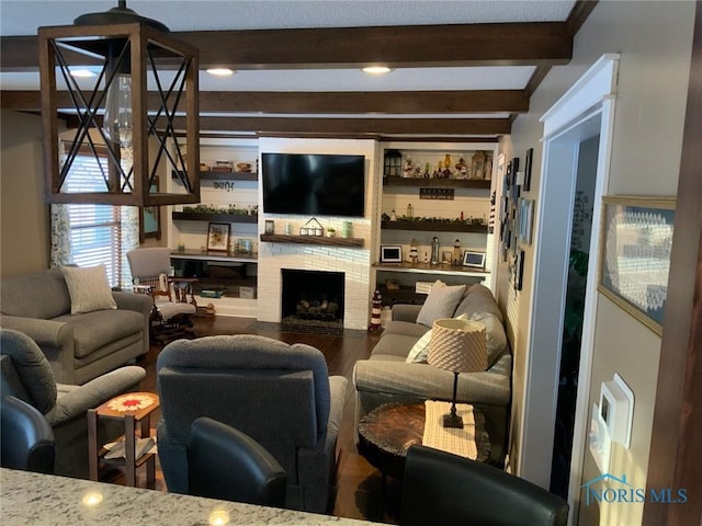 living area featuring beamed ceiling, wood finished floors, and a fireplace