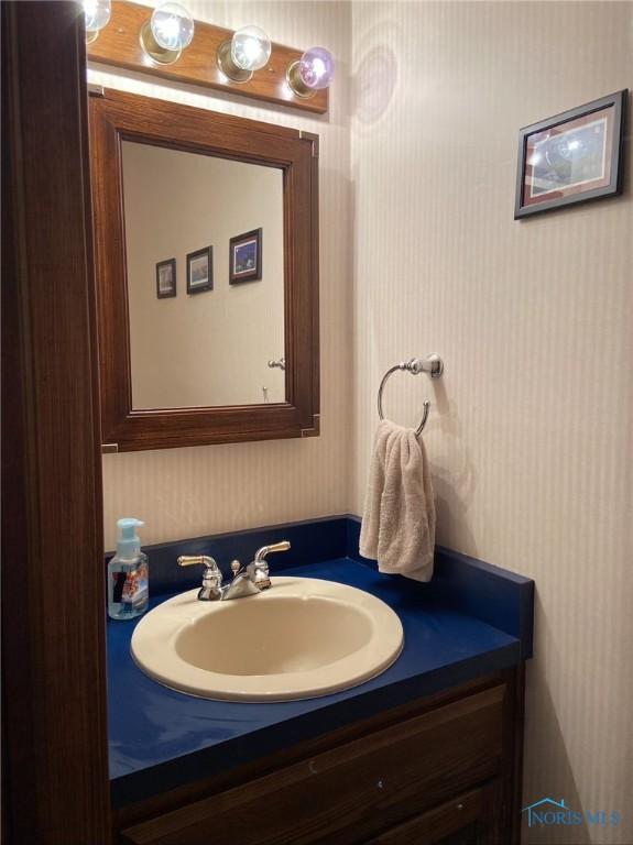 bathroom with wallpapered walls and vanity