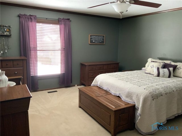 bedroom with visible vents, light colored carpet, ornamental molding, and a ceiling fan