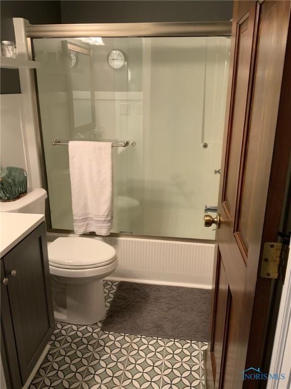 bathroom featuring tile patterned floors, bath / shower combo with glass door, vanity, and toilet