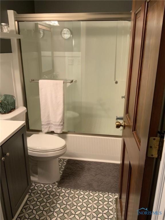 bathroom with combined bath / shower with glass door, vanity, tile patterned floors, and toilet