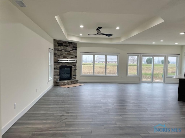 unfurnished living room with visible vents, a raised ceiling, a healthy amount of sunlight, and a fireplace