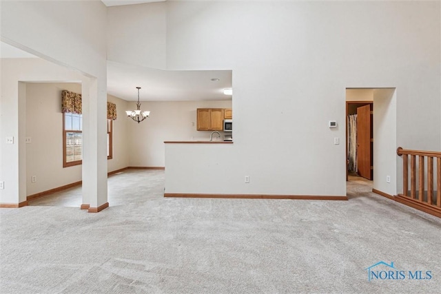 14540 Olde Trail Dr, Perrysburg, OH 43551 - unfurnished living room featuring baseboards, light colored carpet, a high ceiling, and a chandelier