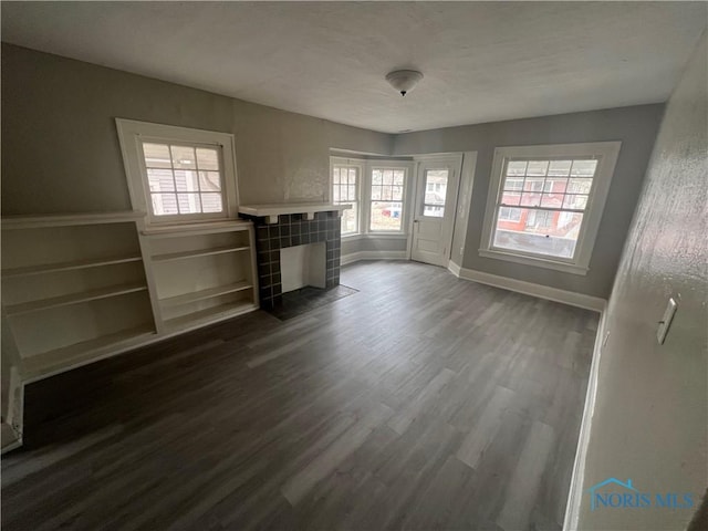 unfurnished living room with baseboards, dark wood-style floors, and a fireplace