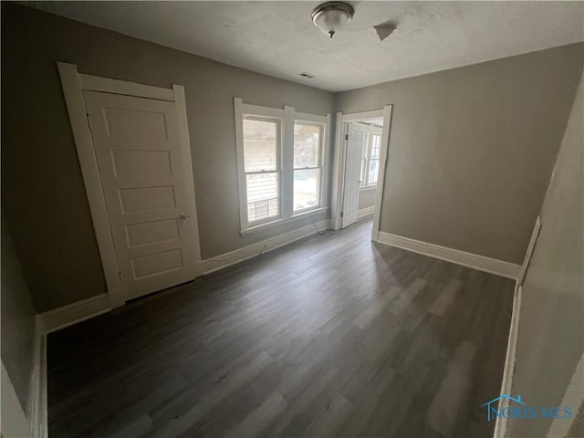 unfurnished bedroom featuring baseboards, a textured ceiling, and wood finished floors