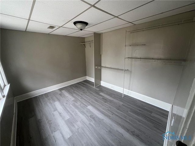 unfurnished bedroom with visible vents, a paneled ceiling, baseboards, and dark wood-style flooring