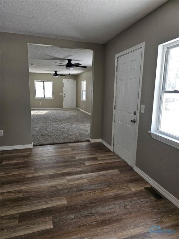 entryway with dark wood finished floors, baseboards, visible vents, and a ceiling fan