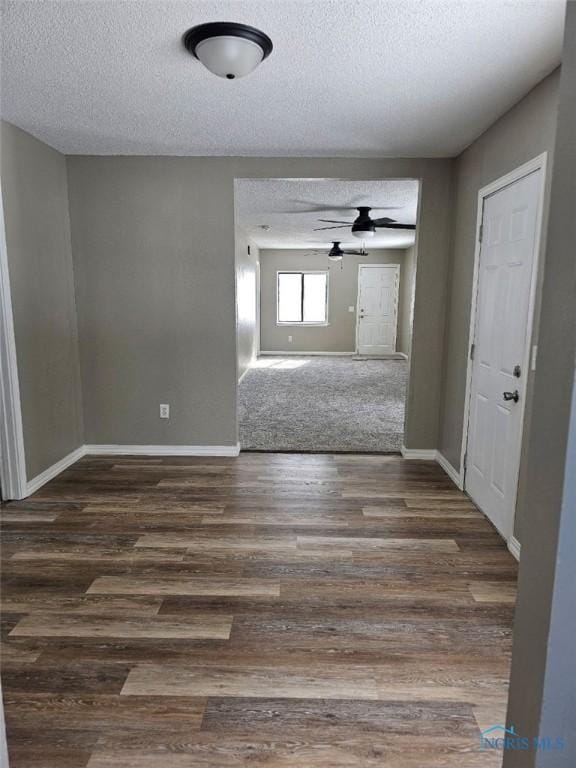 spare room featuring a textured ceiling, dark wood-style floors, baseboards, and a ceiling fan