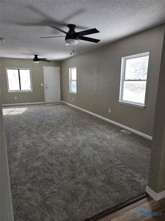unfurnished room with baseboards, a wealth of natural light, visible vents, and ceiling fan