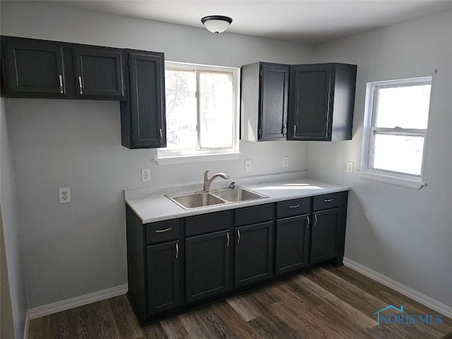 kitchen with dark wood-style flooring, plenty of natural light, baseboards, and a sink