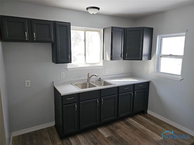 kitchen with a sink, plenty of natural light, dark wood-style floors, and baseboards