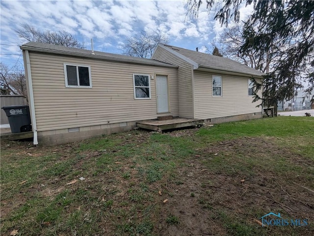 rear view of house with crawl space and a yard